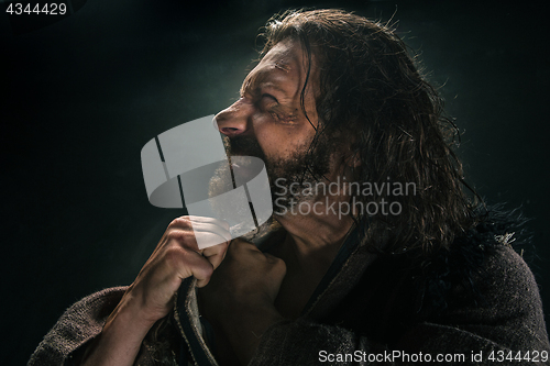 Image of Portrait of a brutal bald-headed viking in a battle mail posing against a black background.