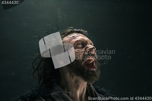 Image of Portrait of a brutal bald-headed viking in a battle mail posing against a black background.