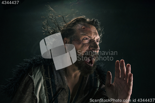Image of Portrait of a brutal bald-headed viking in a battle mail posing against a black background.