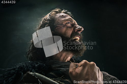 Image of Portrait of a brutal bald-headed viking in a battle mail posing against a black background.