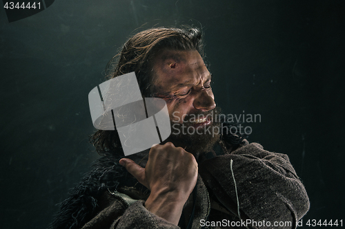 Image of Portrait of a brutal bald-headed viking in a battle mail posing against a black background.