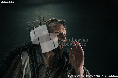 Image of Portrait of a brutal bald-headed viking in a battle mail posing against a black background.