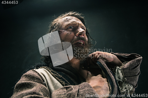 Image of Portrait of a brutal bald-headed viking in a battle mail posing against a black background.