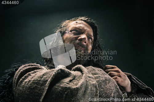 Image of Portrait of a brutal bald-headed viking in a battle mail posing against a black background.