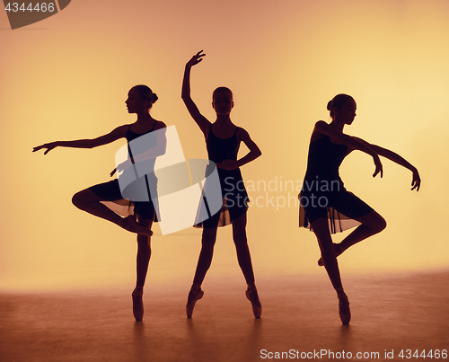 Image of Composition from silhouettes of three young dancers in ballet poses on a orange background.