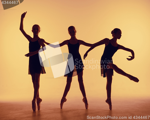 Image of Composition from silhouettes of three young dancers in ballet poses on a orange background.