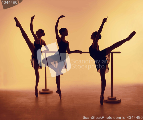 Image of Composition from silhouettes of three young dancers in ballet poses on a orange background.