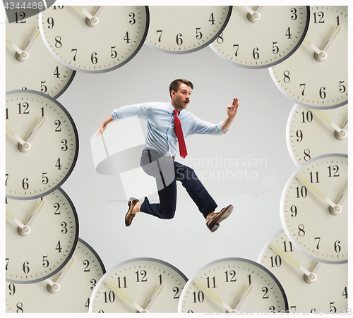 Image of Businessman running over alarm clock.