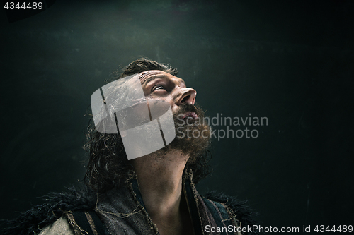 Image of Portrait of a brutal bald-headed viking in a battle mail posing against a black background.