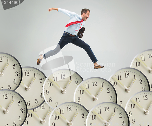 Image of Businessman running over alarm clock.