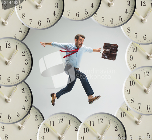 Image of Businessman running over alarm clock.