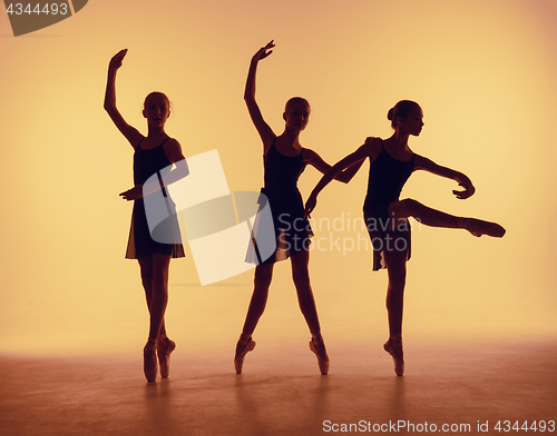 Image of Composition from silhouettes of three young dancers in ballet poses on a orange background.