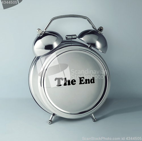 Image of The conceptual image of alarm clock with word THE END on gray studio background