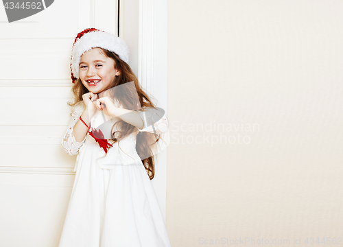 Image of little cute girl in santas red hat waiting for Christmas gifts. 