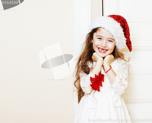 Image of little cute girl in santas red hat waiting for Christmas gifts. 