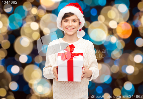 Image of smiling happy boy in santa hat with christmas gift