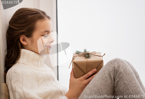 Image of girl with christmas gift sitting at home