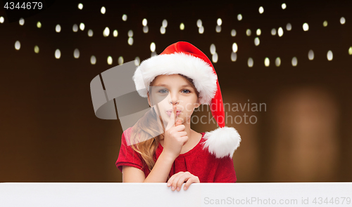 Image of girl in santa hat with board making hush gesture 