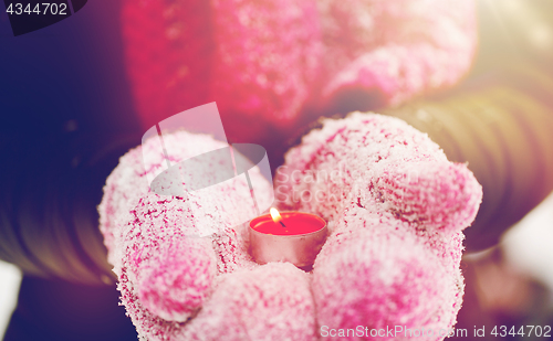 Image of close up of hands in winter mittens holding candle