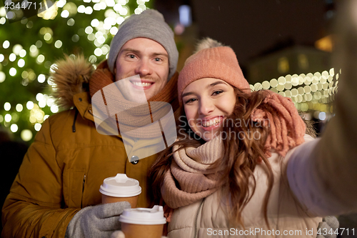 Image of couple with coffee taking selfie at christmas