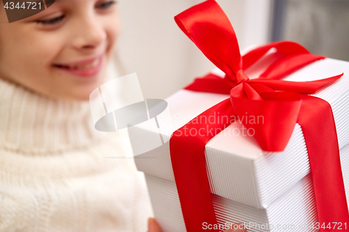 Image of girl with christmas gift sitting on sill at home