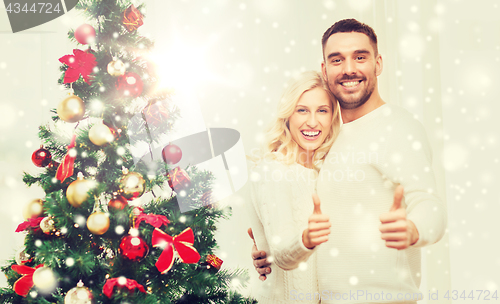 Image of happy couple showing thumbs up with christmas tree