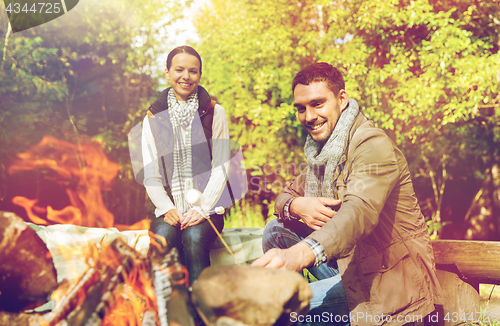 Image of happy couple roasting marshmallow over camp fire