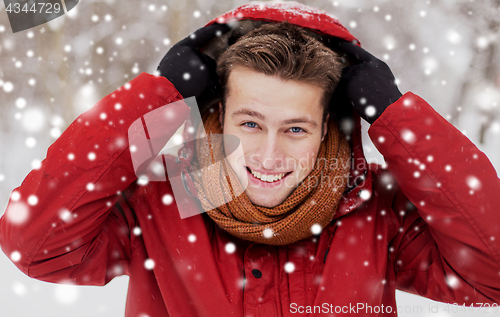 Image of happy man in winter jacket with hood outdoors