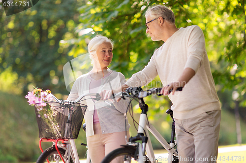 Image of happy senior couple with bicycles at summer park