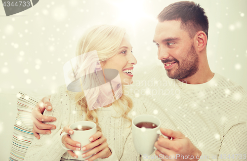 Image of happy couple with cups drinking tea at home