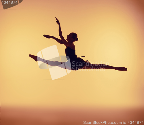 Image of Beautiful young ballet dancer jumping on a orange background.