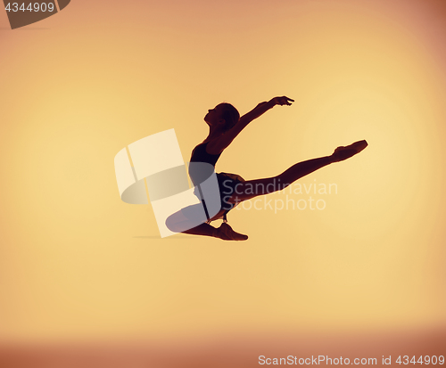 Image of Beautiful young ballet dancer jumping on a orange background.