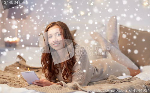 Image of happy young woman with notebook in bed at home