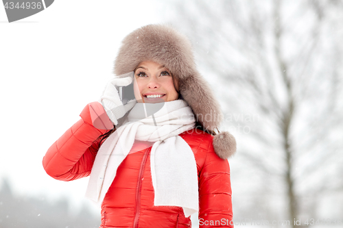 Image of happy woman in winter hat calling on smartphone