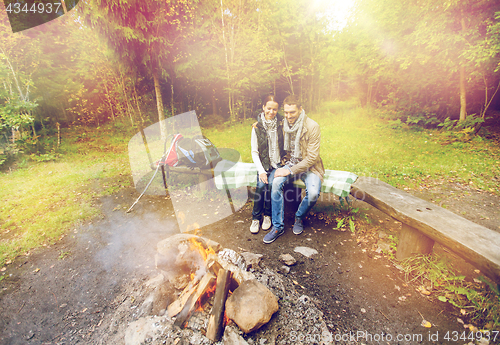 Image of happy couple sitting on bench near camp fire