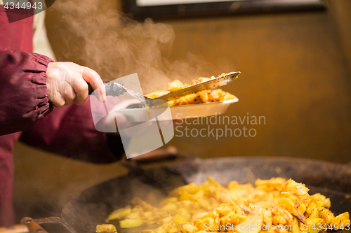 Image of cook with fried potato on plate and turner