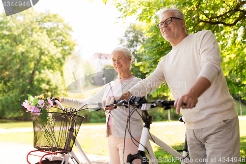 Image of happy senior couple with bicycles at summer park