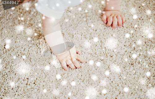 Image of hands of baby crawling on floor or carpet