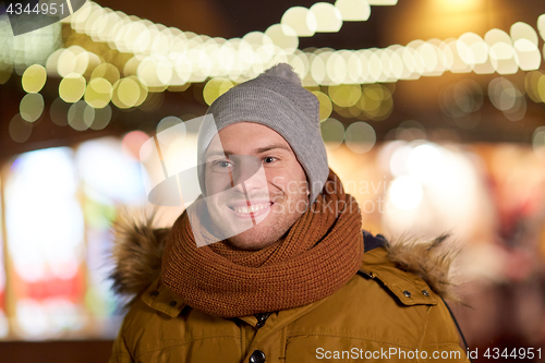 Image of happy young man over christmas lights in winter