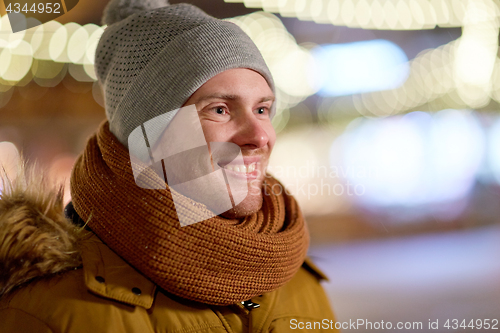 Image of happy young man over christmas lights in winter