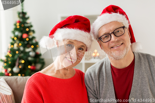 Image of happy senior couple in santa hats at christmas