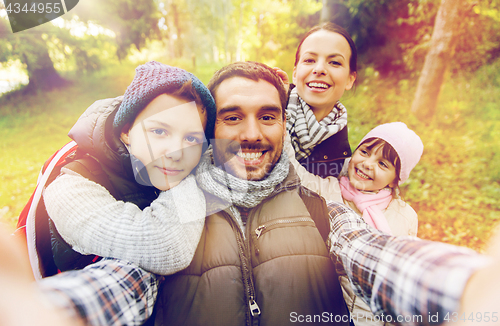 Image of family with backpacks taking selfie and hiking