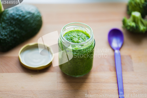 Image of jar with puree or baby food on wooden board