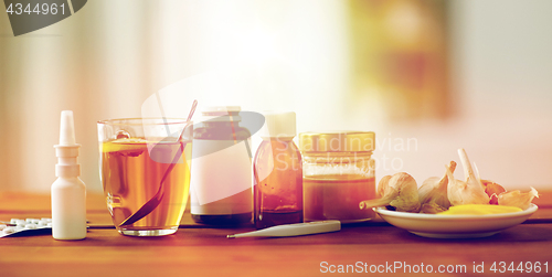 Image of drugs, thermometer, honey and cup of tea on wood