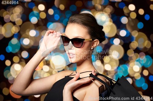 Image of happy woman in black sunglasses with shopping bags