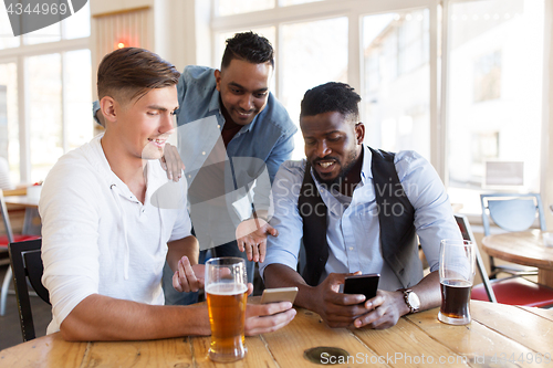 Image of male friends with smartphone drinking beer at bar