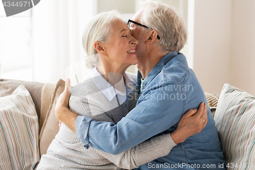 Image of happy senior couple hugging at home