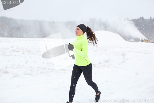 Image of happy smiling woman running outdoors in winter