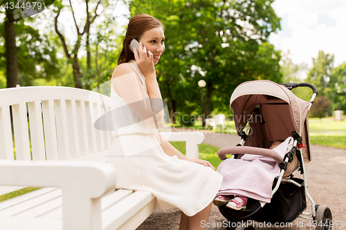 Image of mother with stroller calling on smartphone at park