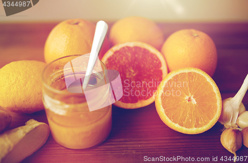 Image of honey, citrus fruits, ginger and garlic on wood